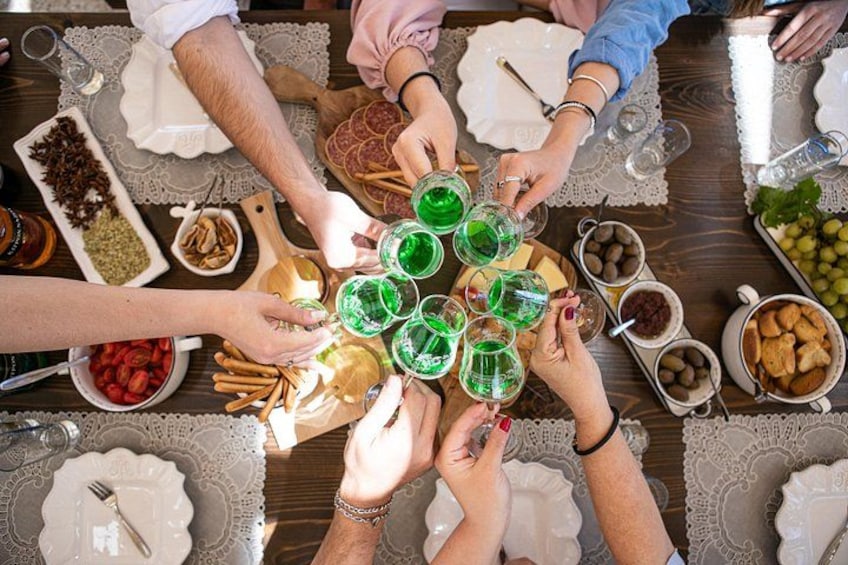 A group of people toasting with green drinks around a table with various food items. 3