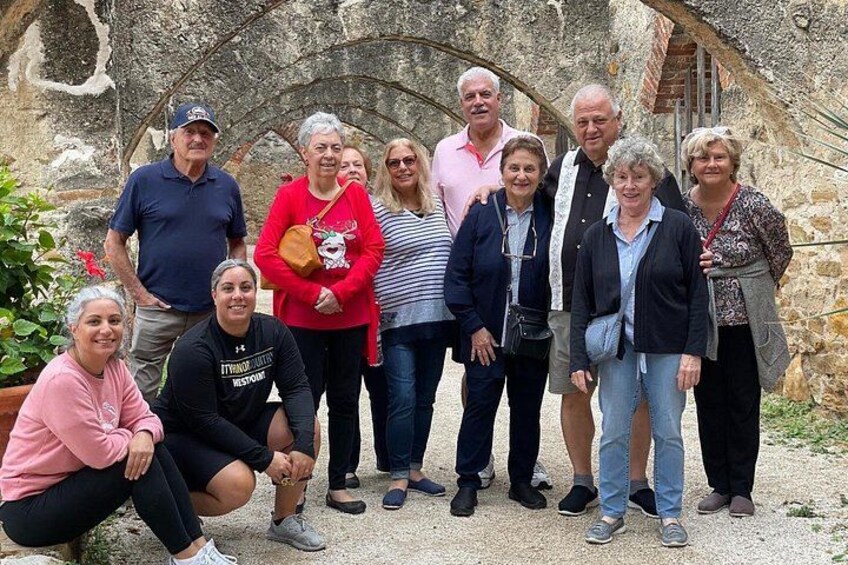 Un gruppo di persone in piedi di fronte a un arco in pietra. 3