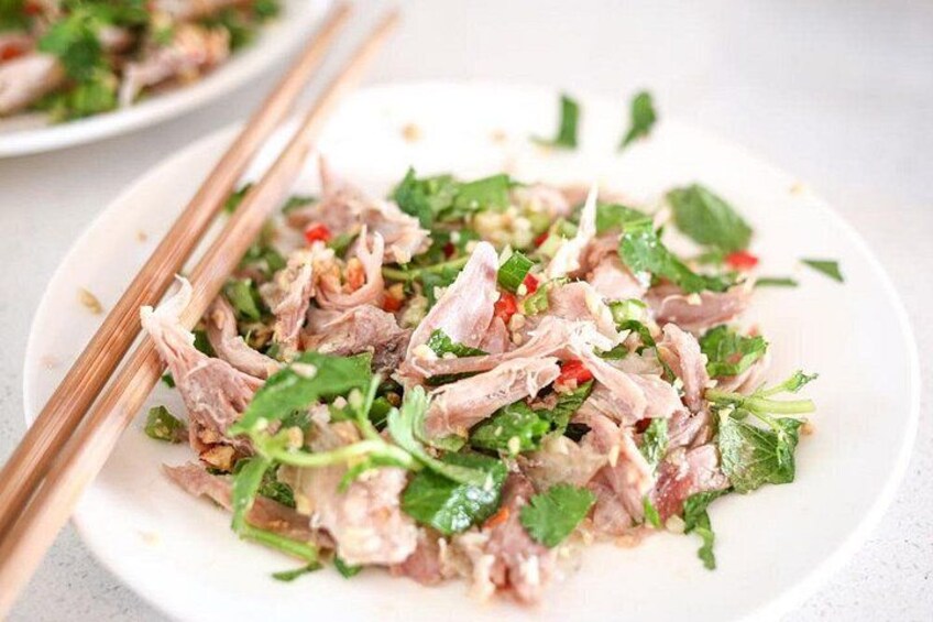 A plate of sliced meat with herbs and vegetables. 3