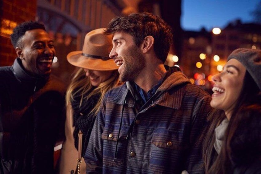 A group of people outdoors at night, with city lights in the background. 2