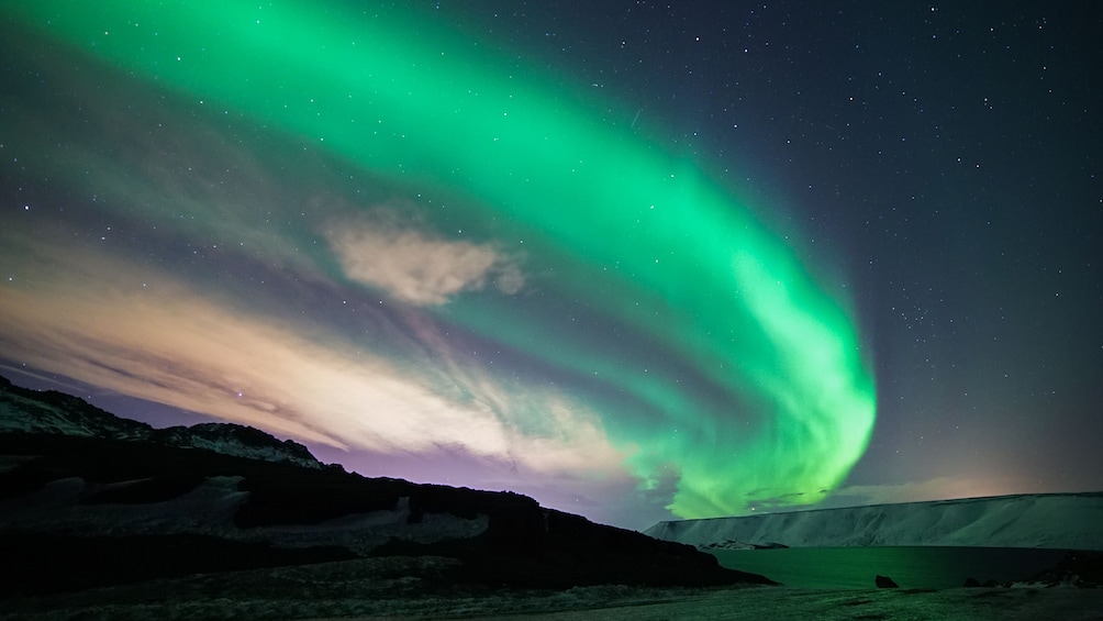 The Northern Lights over a snowy landscape with a mountain in the foreground. 3