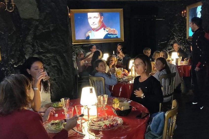 A group of people dining at a restaurant with a large screen displaying a movie. 1