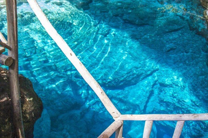 Cubierta de madera sobre agua azul cristalina con formaciones rocosas visibles debajo. 2