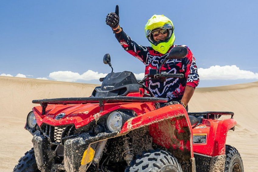 A person on a red ATV in a desert with sand dunes. 5