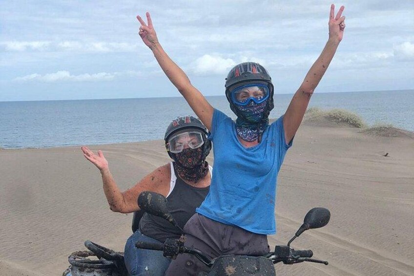 Two people on a dune buggy with the ocean in the background. 3