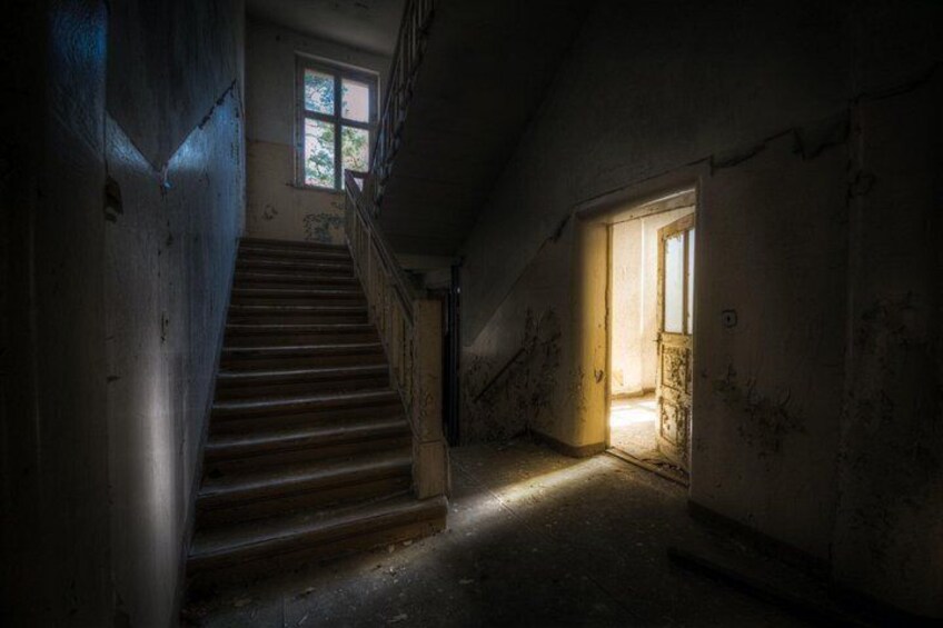 A dimly lit staircase leading to a room with a window and a door. 1