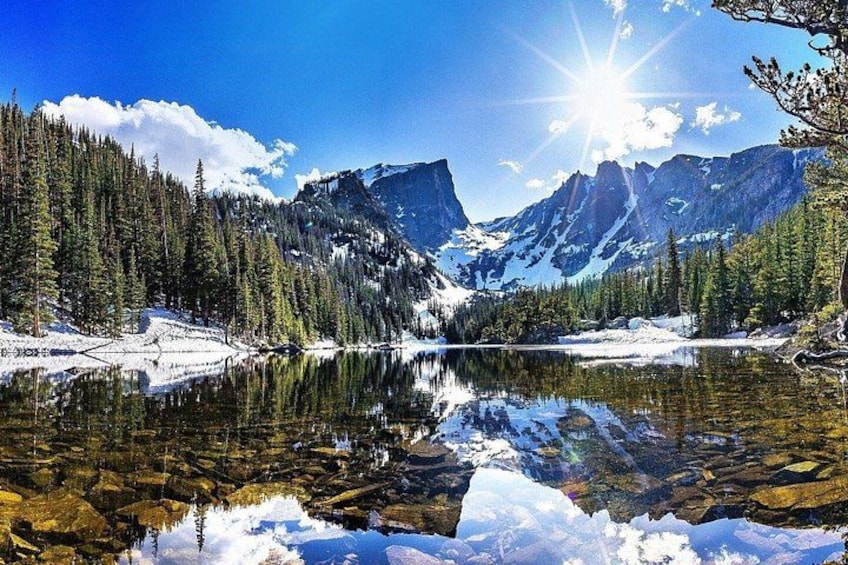 Paisaje montañoso con un lago, picos nevados y un bosque denso. 2