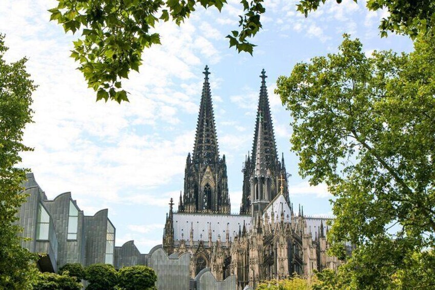 Eine gotische Kathedrale mit zwei hohen Türmen, umgeben von Bäumen und modernen Gebäuden. 5