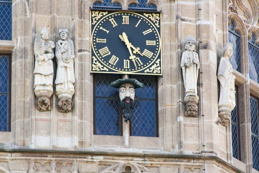Eine Uhr mit römischen Ziffern und einem Zifferblatt mit Gesichtsmaske. 2