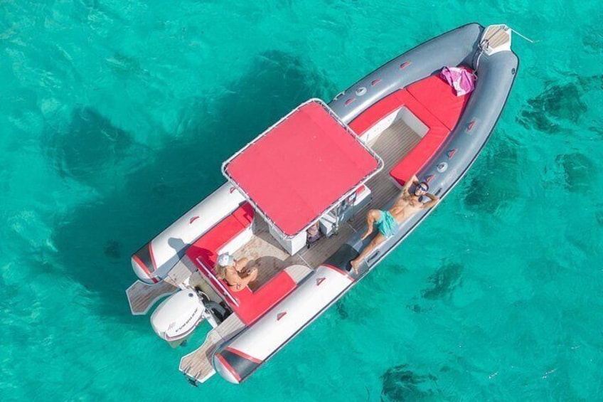 An inflatable boat with a red canopy, a person seated at the helm, and another person lying down. 1
