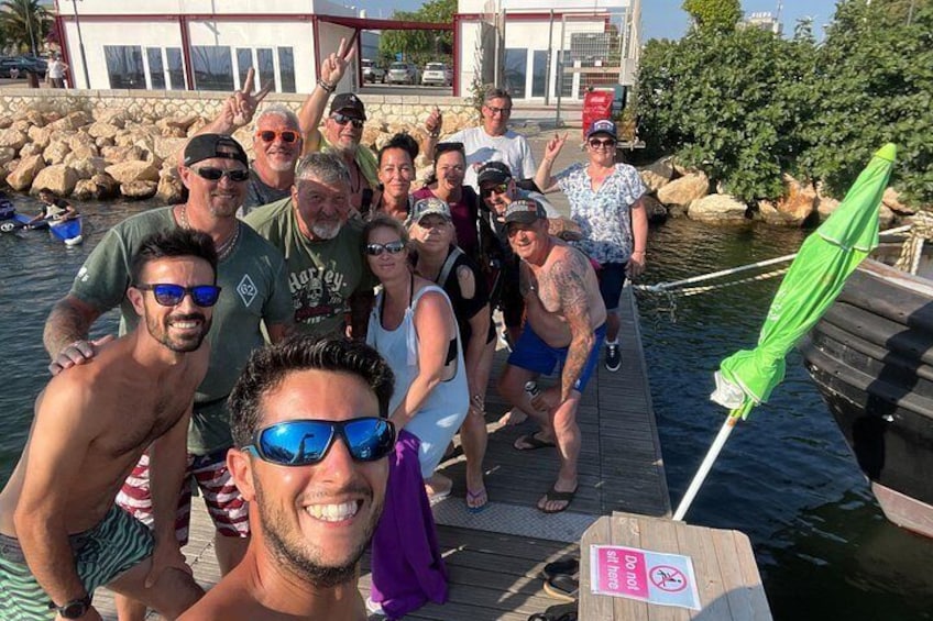 A group of people on a wooden dock by a body of water, with a sign indicating no swimming. 4