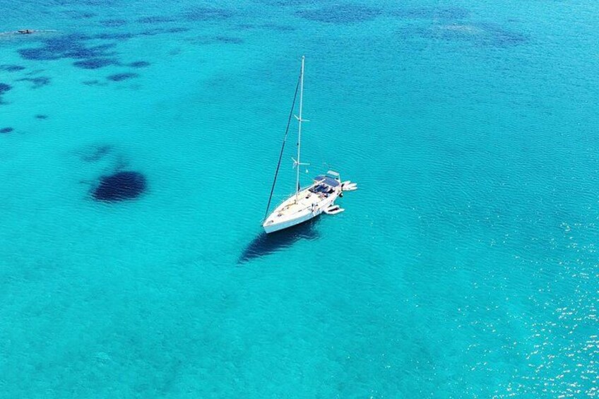 A sailboat anchored in clear turquoise waters with coral formations. 3