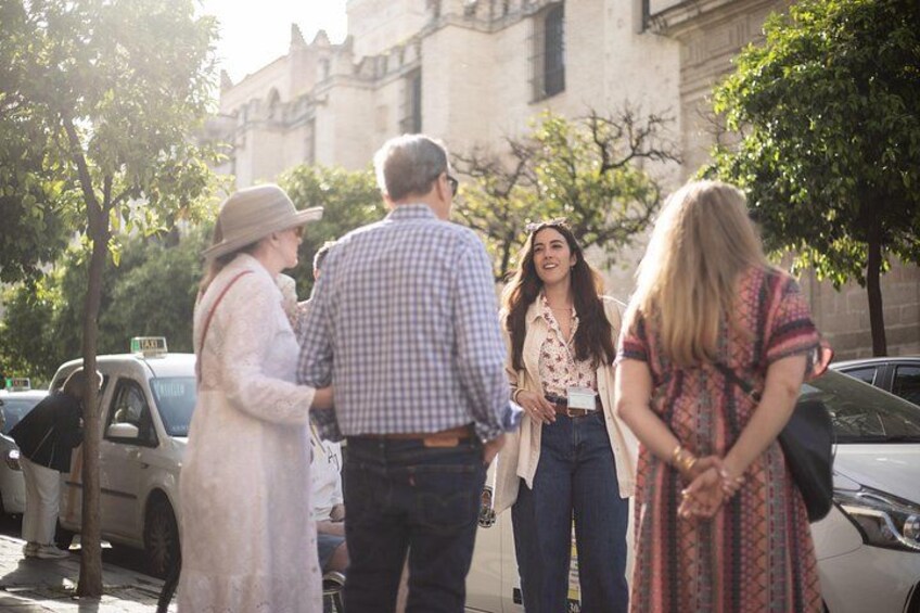 A group of people standing on a street with cars parked nearby and a building in the background. 2