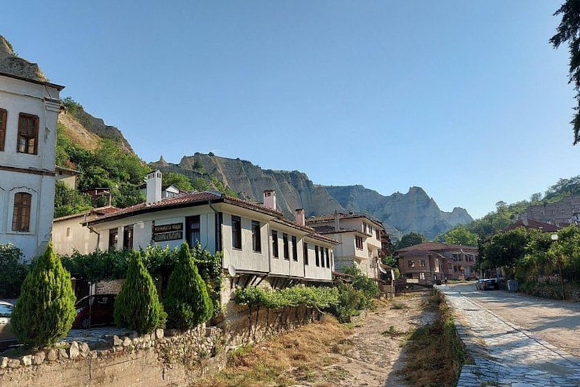 A street with buildings, a stone wall, and mountains in the background. 2