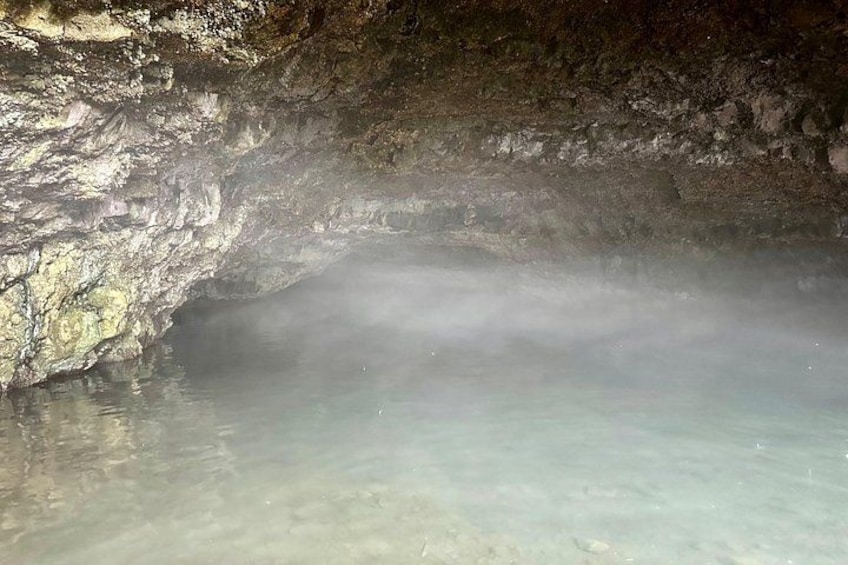 A cave with clear water and a visible rock formation. 2