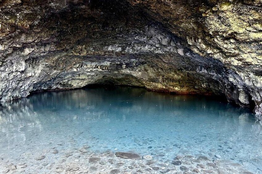 Eine Höhle mit klarem, blauem Wasser und steinernen Wänden. 4
