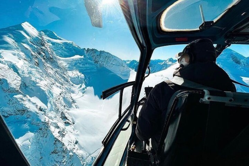 A helicopter cockpit with a view of snow-covered mountains and a clear sky. 4