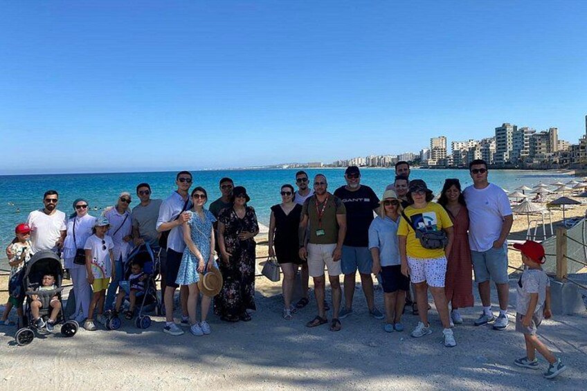 A group of people standing on a beach with a city skyline in the background. 3