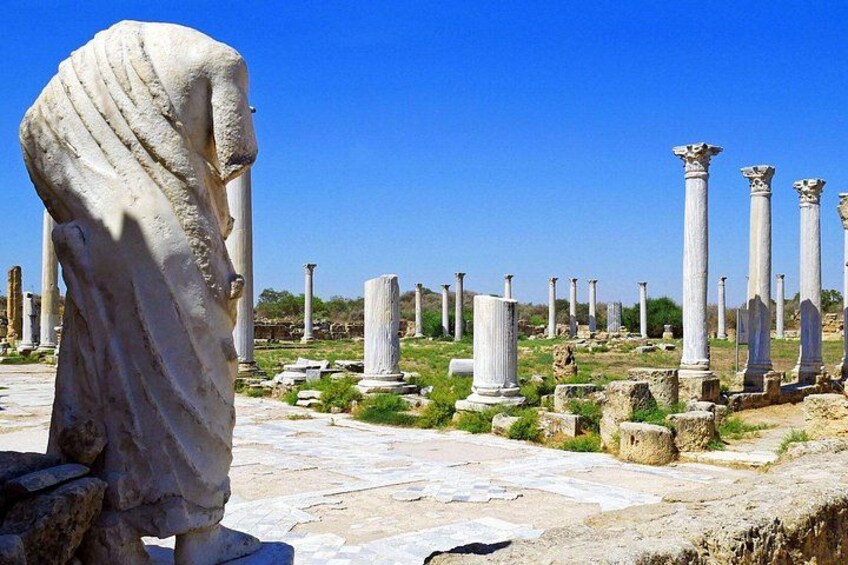 Ancient ruins with columns and a large stone statue. 4
