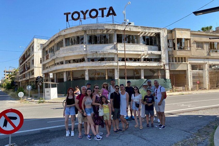 A group of people posing in front of a building with a 'TOYOTA' sign. 1
