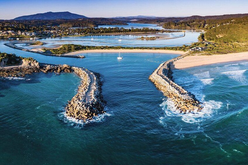 Un paisaje costero con un río sinuoso, una playa arenosa y un rompeolas rocoso. 2