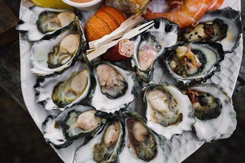 Un plato de ostras con cuñas de limón y un trozo de salmón. 5