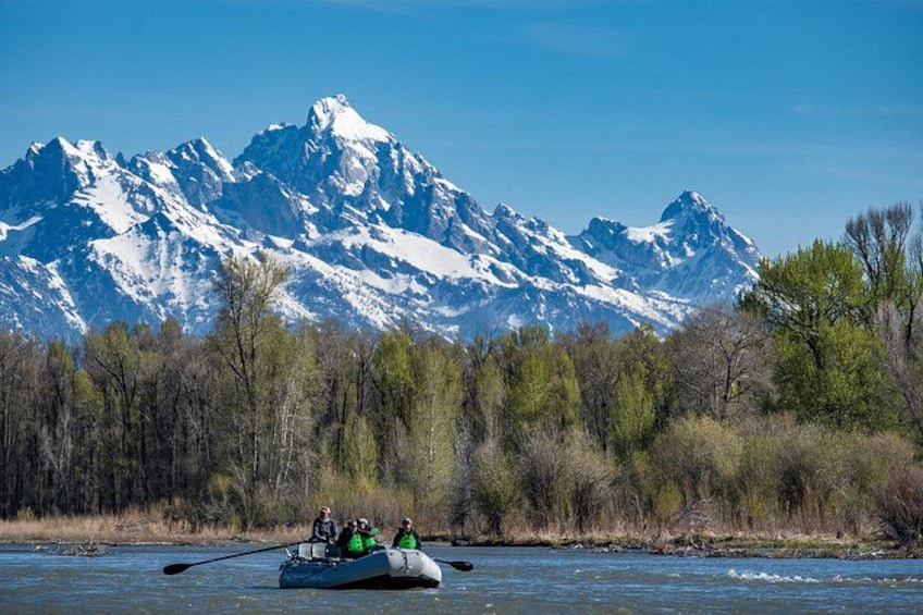 A river with a boat, mountains in the background, and trees along the riverbank. 3