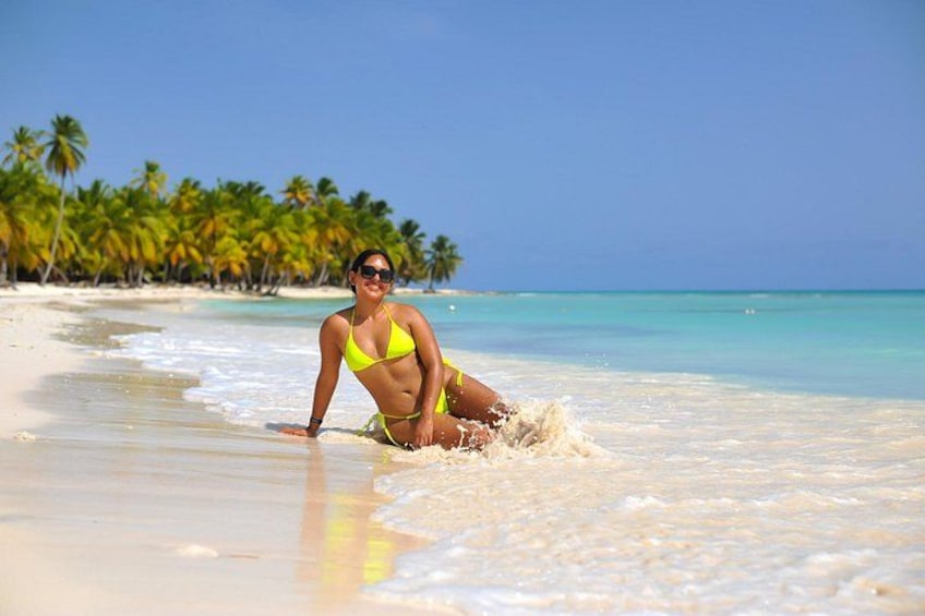 Une personne portant un bikini jaune sur une plage de sable, avec des palmiers en arrière-plan. 1