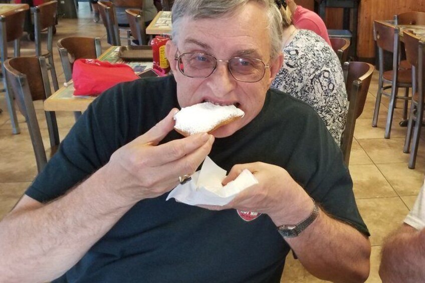 A person sitting at a table in a restaurant, eating a pastry. 4