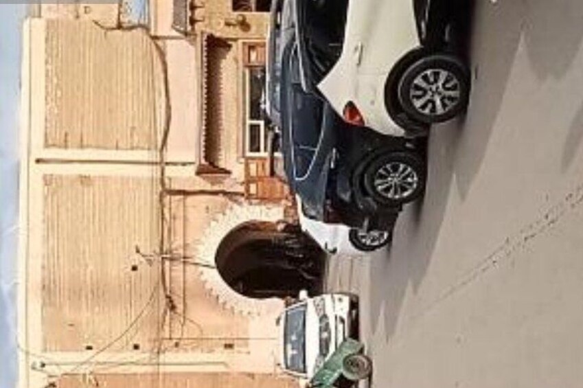 Une voiture blanche est garée dans une rue, avec un bâtiment en arrière-plan. 2