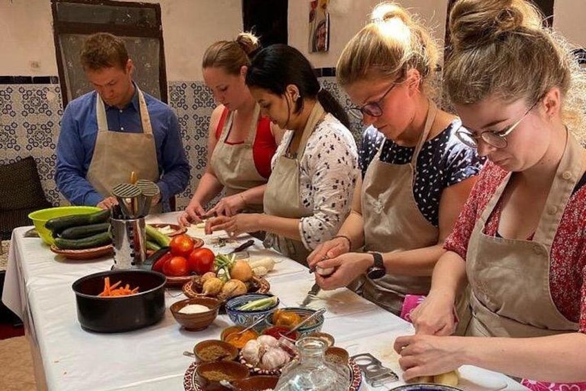 Un groupe de personnes prépare des aliments à une table, avec des légumes et des ustensiles de cuisine. 2