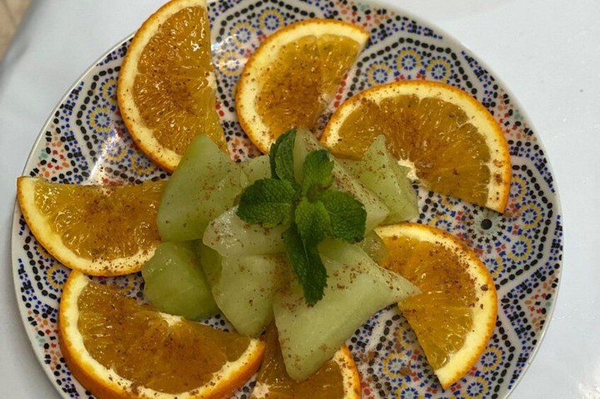 A plate with sliced oranges and a mint garnish. 4