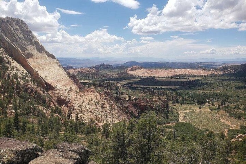 Un paisaje montañoso con un valle, árboles y cielo despejado. 2