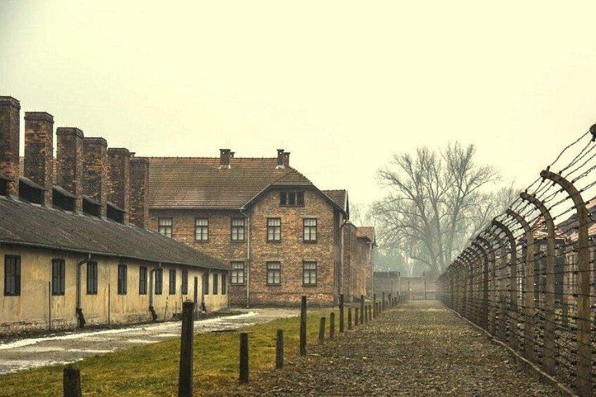 A historical building with a long, straight fence in the foreground. 2