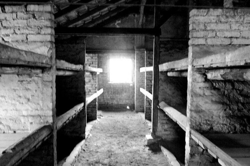 A rustic, dimly lit room with exposed brick walls and wooden beams. There is a window allowing natural light to enter, and a ladder leading to an upper level. 3