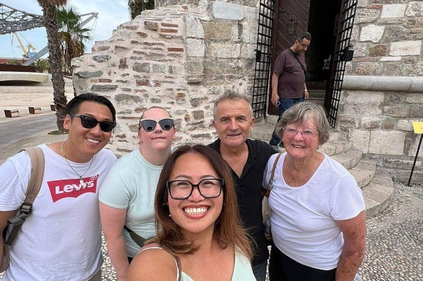 A group of people standing in front of a stone building with a gate. 3