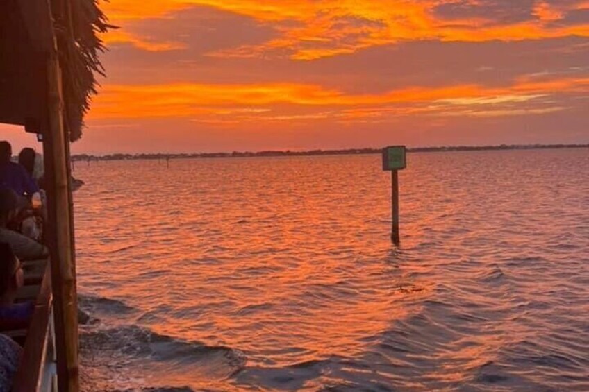 A sunset over a body of water with a floating structure and a sign in the distance. 3