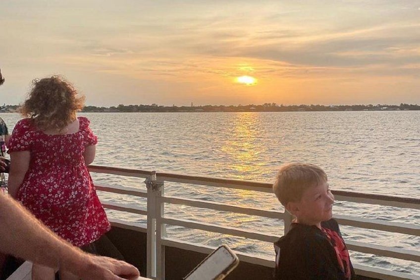A sunset over a body of water with a railing in the foreground. 3