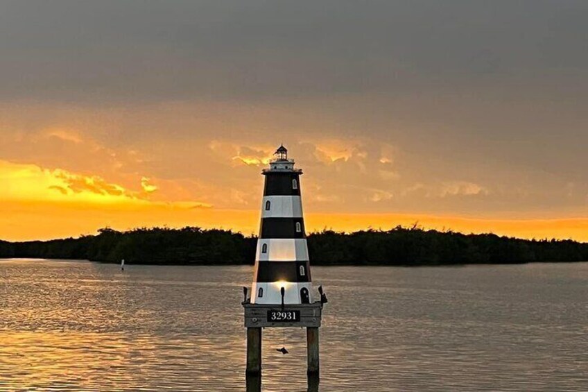 A lighthouse at sunset with a clear sky and calm water. 5
