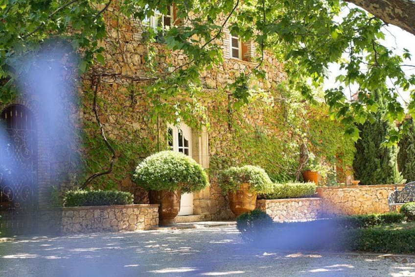 A stone building with ivy, a well-kept garden, and a clear sky. 4