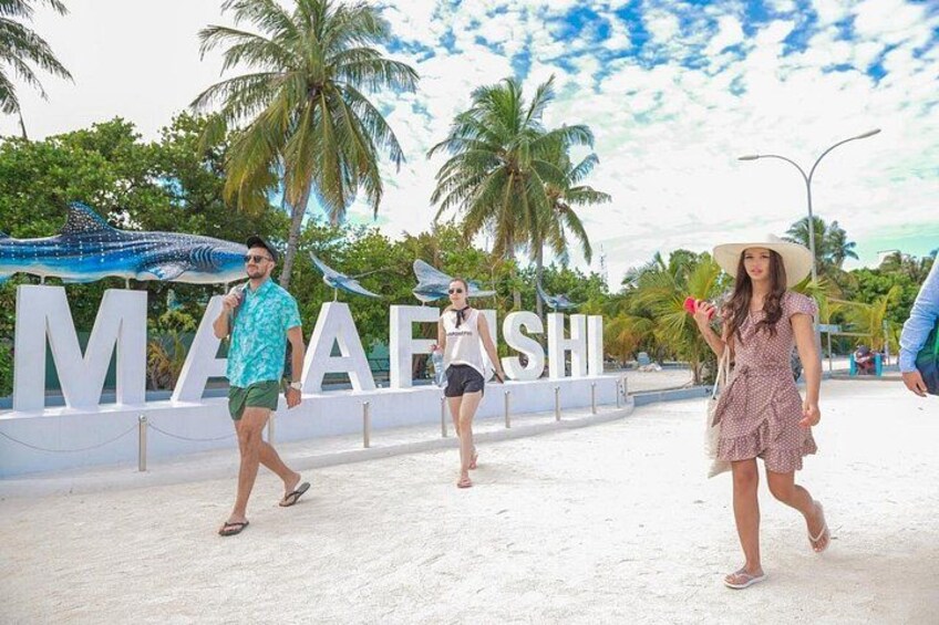 A beachside walkway with palm trees and a large sign reading 'MAAFASHI'. 3