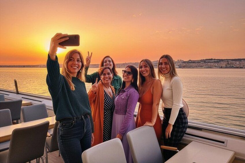 Un groupe de personnes prenant un selfie sur un bateau, avec un coucher de soleil en arrière-plan. 1