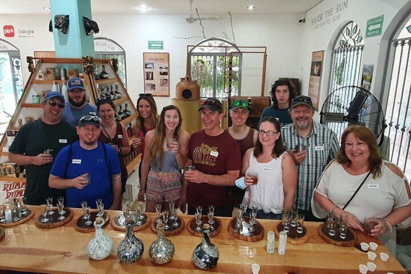 A group of people standing around a table with various bottles and glasses. 3