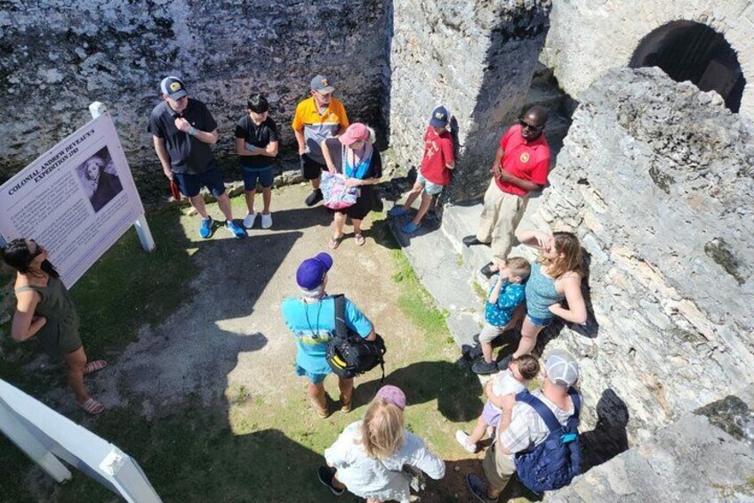 A group of people gathered around a historical site with a signboard. 3