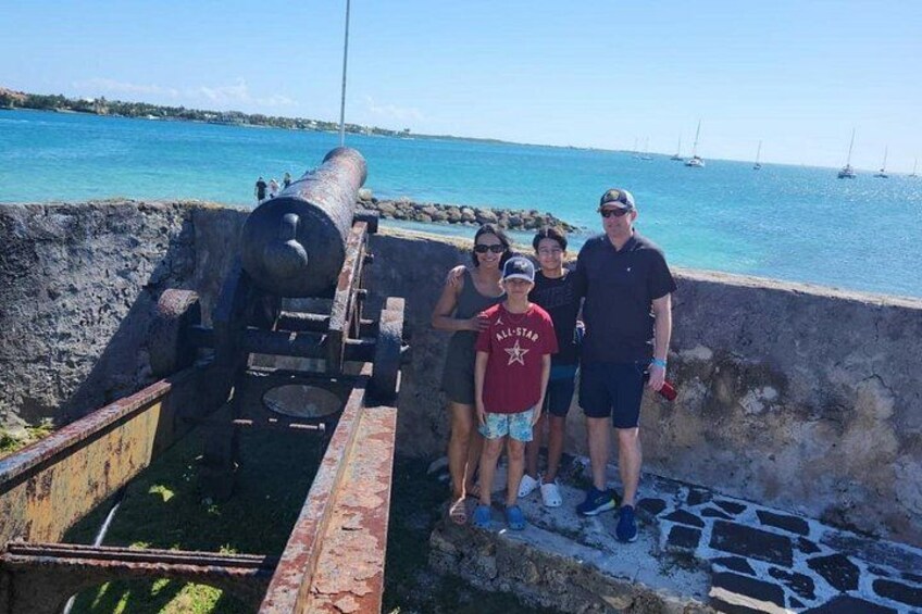 A cannon, a group of people, and a coastal landscape with clear skies. 3