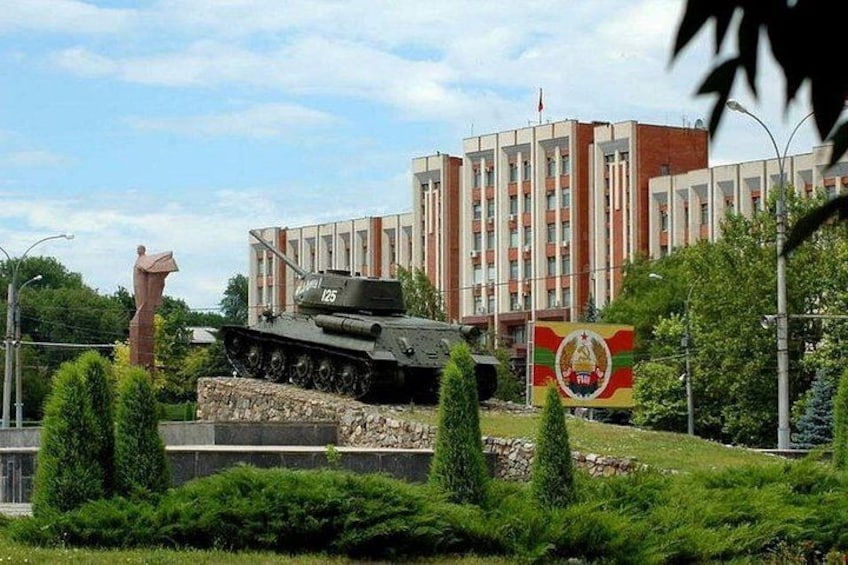 Un char d’assaut, une statue et un bâtiment arborant un drapeau. 1