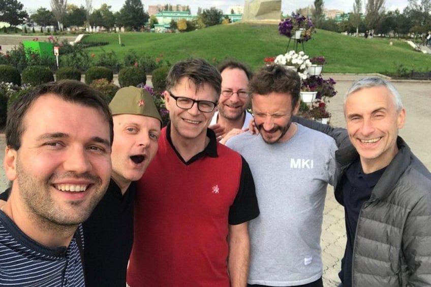 Un groupe de personnes se tient à l’extérieur, sur une pelouse, avec un monument en arrière-plan. 3