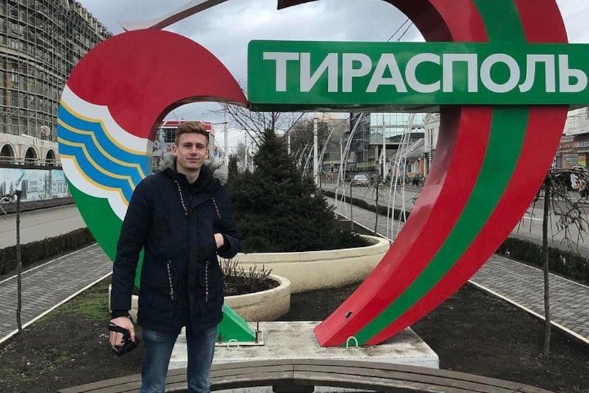 Une personne se tient devant une grande enseigne colorée sur laquelle on peut lire le mot « Тирасполь ». 4