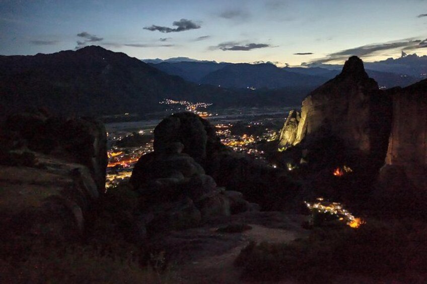 Un paysage montagneux au crépuscule, avec une ville illuminée dans la vallée en contrebas. 3