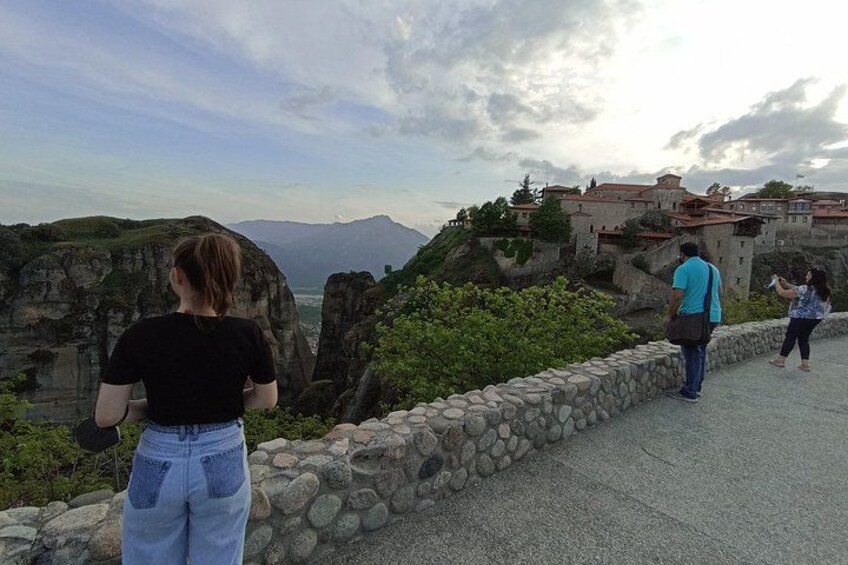 Un sentier de pierres offrant une vue sur un paysage montagneux et un bâtiment dont le toit est recouvert de tuiles rouges. 2
